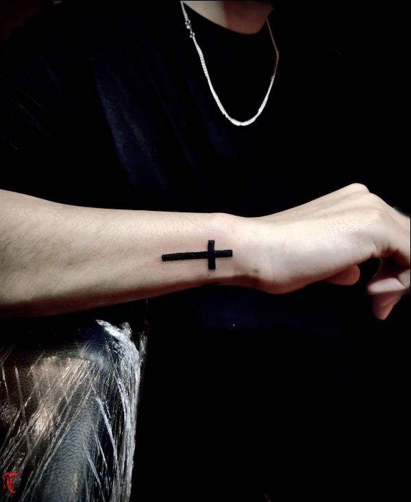 black cross tattoo on wrist